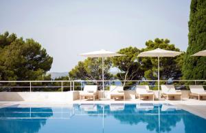 een zwembad met witte stoelen en parasols bij Bluesun Hotel Maestral in Brela