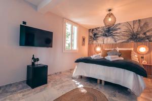 a bedroom with a bed with a tv on the wall at Les Suites de l'Étang in Cucuron