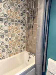 a bathroom with a tub and a shower with tiles at Coastland Holiday Park in Manorbier