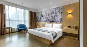 um quarto de hotel com uma cama grande e uma cadeira azul em City Comfort Inn Hengyang Nanhua 2nd Affiliated Jinxiu Pearl em Hengyang