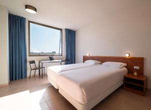 a hotel room with a large bed and a desk at Hesperia Sant Joan in Sant Joan Despí