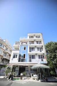 un edificio alto de color blanco con sillas y sombrilla en Family Hotel White House, en Pomorie