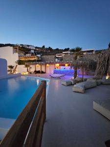 une grande piscine bordée de palmiers et un complexe dans l'établissement Elli Tropical Suites, à Mykonos