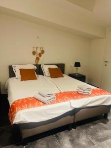 1 dormitorio con 2 camas con sábanas de color naranja y blanco en Equus B&B en Bredene