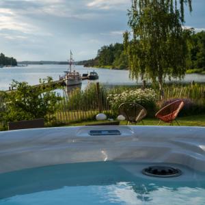 a hot tub with a view of a river and a boat at Skeviks Gård in Gustavsberg