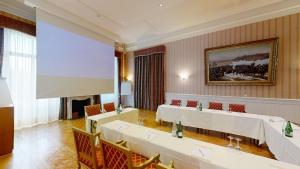 a meeting room with tables and chairs and a large screen at Golf Hotel René Capt in Montreux