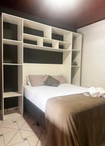 1 dormitorio con 1 cama con estanterías blancas en BLUE DOOR BRASIL en Ilha Grande