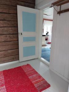 um quarto com uma porta e um tapete vermelho em 200 years old small cottage with sauna close to archipelago em Töfsala