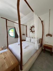 una camera con letto a baldacchino e lenzuola bianche di Quma Hotel a Gili Trawangan