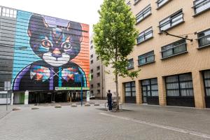 eine Person auf einem Fahrrad vor einem Gebäude mit einer Katze darauf in der Unterkunft City Hotel Hengelo in Hengelo