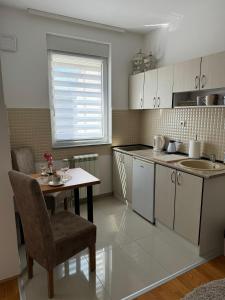 eine Küche mit einem Tisch und einem Waschbecken sowie einem Tisch und Stühlen in der Unterkunft Angellina Apartmani in Sremska Mitrovica