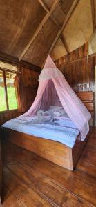 Una cama con mosquitera encima. en Monkey Business Tours and Accommodation en Bukit Lawang