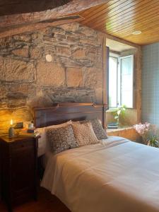 a bedroom with a large bed with a stone wall at Casa Grande de Láncara in Lugo