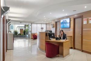 une femme assise au comptoir dans le hall de l'hôpital dans l'établissement Hotel Delfino Lugano, à Lugano