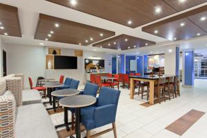 奧克蘭的住宿－Holiday Inn Express & Suites Oakland - Airport, an IHG Hotel，一个带桌椅的大堂和一间自助餐厅