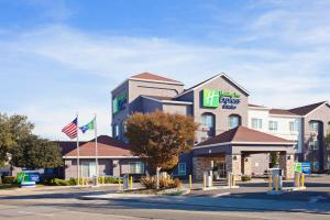 奧克蘭的住宿－Holiday Inn Express & Suites Oakland - Airport, an IHG Hotel，大楼前有旗帜的酒店