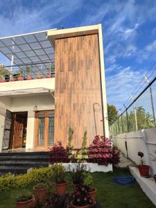 una casa con una pared de madera en el patio en Kodai Diva Inn - Home Stay en Kodaikānāl