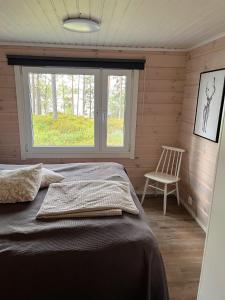 um quarto com uma cama, uma cadeira e uma janela em Kalliorinne em Kuusamo