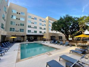 una piscina frente a un hotel con sillas y un edificio en Cambria Hotel Austin Uptown near the Domain en Austin