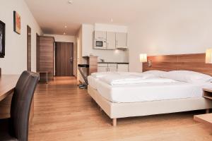 1 dormitorio con 1 cama blanca grande y cocina en Fairmotel Dornbirn, en Dornbirn