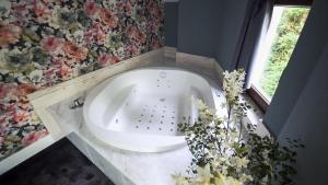 baño con bañera blanca y flores en Hotel Cuevas - Adults Only en Santillana del Mar