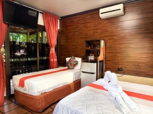 a bedroom with two beds and a television in it at Hotel Heliconias Nature Inn & Hot Springs in Fortuna