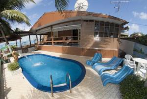 une piscine avec deux chaises bleues et une maison dans l'établissement Pousada Além dos Mares, à Fernando de Noronha