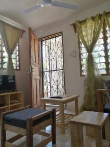 Moringa Garden Cottage, mombasa, north coast, kikambala في متوابا: غرفة معيشة مع طاولة ونوافذ