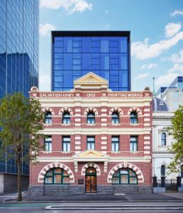 ein rotes Backsteingebäude vor einem hohen Gebäude in der Unterkunft Lanson Place Parliament Gardens in Melbourne