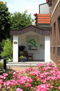 a building with a bench in a garden with pink flowers at Hotel Am Steinberg in Hildesheim