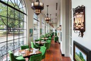 um restaurante com cadeiras verdes, mesas e janelas em The St. Anthony, a Luxury Collection Hotel, San Antonio em San Antonio