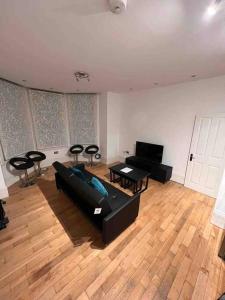 sala de estar con sofá negro y sillas en 2 bed garden flat West Dulwich FREE STREET PARKING en Londres