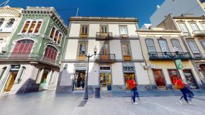 twee mensen die door een straat lopen voor gebouwen bij Triana Rooms EH in Las Palmas de Gran Canaria