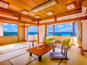 een woonkamer met ramen en een tafel en stoelen bij Ooedo Onsen Monogatari Shima Saichoraku in Shima