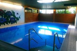 een groot zwembad met blauw water in een kamer bij Ferienwohnung am Weissensee mit Pool,Sauna in Füssen