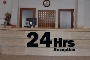 un mostrador de recepción con una señal de recepción de horas en Tasmaria Aparthotel en Pafos