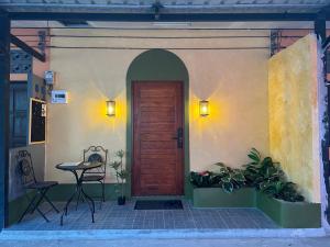 una puerta delantera de una casa con una mesa y una silla en Sierra Hostel en Nai Yang Beach