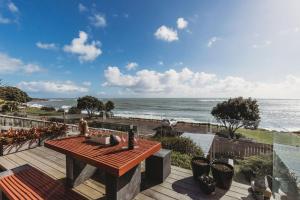 une terrasse en bois avec une table et une vue sur l'océan dans l'établissement Te Moana Waterfront, à New Plymouth