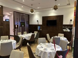 um restaurante com mesas e cadeiras brancas e uma televisão de ecrã plano em Vinpy hotels em Uyo