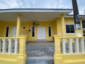 un edificio amarillo con una puerta blanca y columnas en BARAKAH HOMESTAY en Kota Tinggi