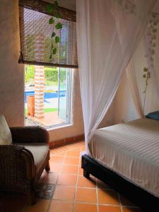 1 dormitorio con cama, ventana y silla en Coccoloba en Flandes