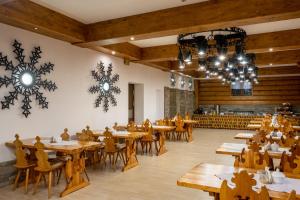 ein Restaurant mit Holztischen, Stühlen und Kronleuchtern in der Unterkunft Dom Wczasowy Grań in Zakopane