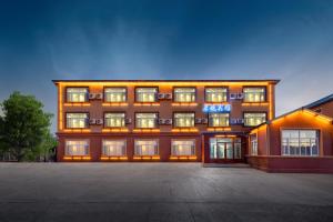 un gran edificio con muchas ventanas en un estacionamiento en Qihang Hotel Harbin Taiping Airport en Harbin