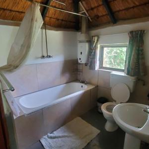 e bagno con vasca, servizi igienici e lavandino. di Mashai Rest Rondavel a Underberg