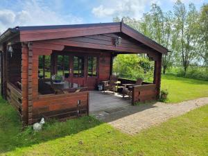 eine Holzhütte mit einer Holzterrasse im Gras in der Unterkunft Op e Mieden 