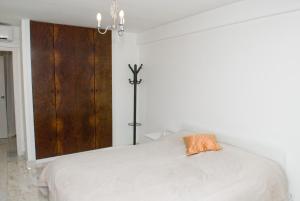 een slaapkamer met een wit bed met een oranje kussen erop bij Porto Sea Apartments in Matosinhos