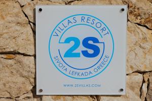 a sign for the marias responseagency on a stone wall at 2S Villas Resort in Sivota