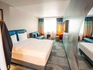 ibis Styles St Margrethen Bodensee في سانكت مارغريثين: غرفه فندقيه بسرير واريكه