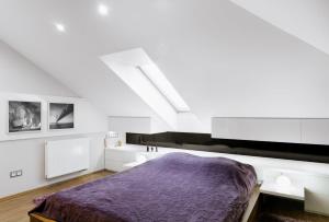 - une chambre blanche avec un lit violet dans l'établissement Wrzosowy Apartament, à Sosnowiec