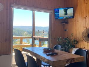 uma mesa de madeira com cadeiras e uma televisão na varanda em Cabaña La Puntilla em Vichuquén